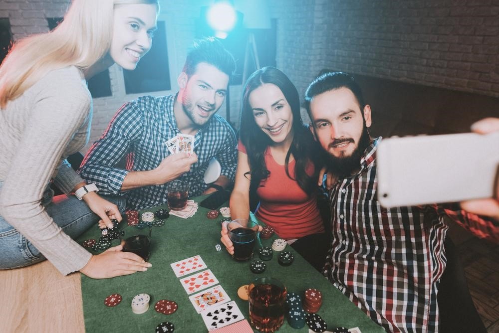 group friends of taking a selfie while enjoying a game of poker